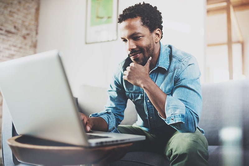 Man on laptop shopping for cars from home